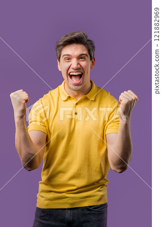 Handsome man on violet,shows triumph yes YEAH gesture of victory,achieved result 121882969