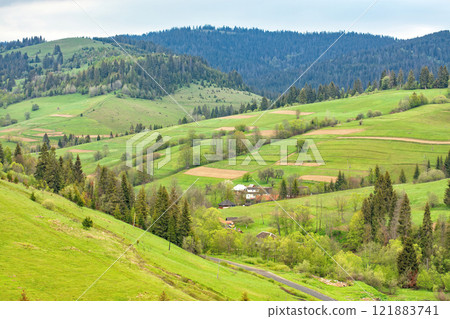 Lush green valleys embrace a tranquil village nestled among the hills of spring 121883741