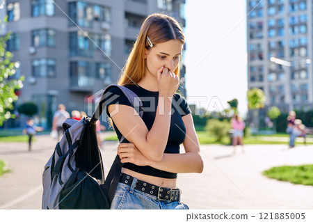 Sad unhappy teenage college student girl with backpack, outdoor, city background 121885005