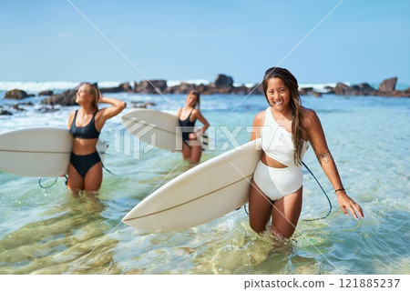 Women surfers with boards in sea water. Smiling Asian woman holding surfboard. Group enjoys tropical beach day, clear blue sky, ocean waves. Surf travel destination for adventurous tourists. Women surfers with boards in sea water. Smiling Asian woman holding surfboard. Group enjoys tropical beach day, clear blue sky, ocean waves. Surf travel destination for adventurous tourists. 121885237