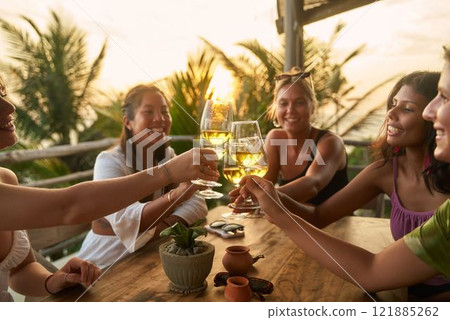 Diverse women toast drinks in beachside restaurant. Friends celebrate at sunset, cheer with wine glasses. Enjoying bachelorette party trip or women club meeting by sea. Diverse women toast drinks in beachside restaurant. Friends celebrate at sunset, cheer with wine glasses. Enjoying bachelorette party trip or women club meeting by sea. 121885262