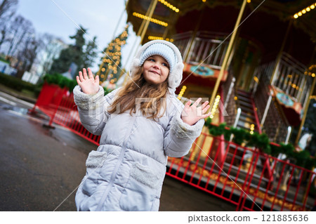Child enjoying winter festivities near a carousel in a festive setting 121885636