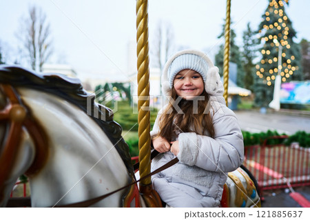 Child enjoys a carousel ride at a festive outdoor location during winter 121885637