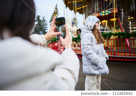 Friends capturing memories at a festive fairground during winter 121885642