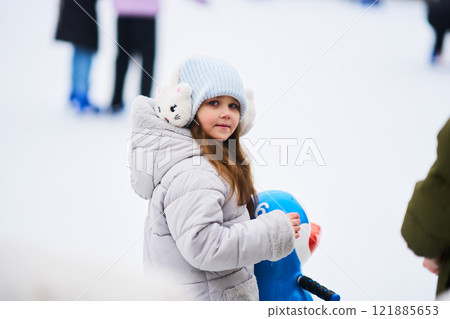 Young child enjoying winter fun at outdoor skating rink in snowy landscape Young child enjoying winter fun at outdoor skating rink in snowy landscape 121885653