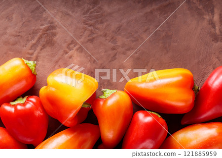 Ripe Red and Orange Capsicum on Brown Background for Vegetarian and Vegan Meals, Copy Space 121885959