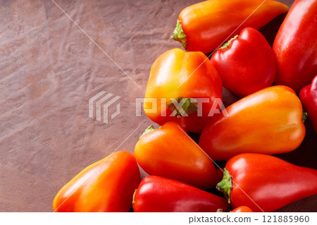 Ripe Red and Orange Capsicum on Brown Background for Vegetarian and Vegan Meals, Copy Space 121885960