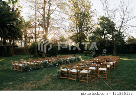 Wooden folding chairs are lined up in a lush green field Wooden folding chairs are lined up in a lush green field 121886132