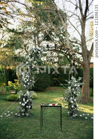 A table sits beneath a tree in the center of green grass A table sits beneath a tree in the center of green grass 121886135
