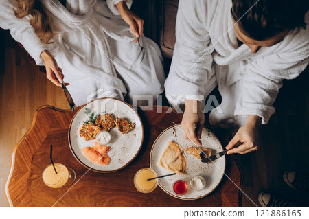 A man and a woman are sitting together at a table enjoying their food A man and a woman are sitting together at a table enjoying their food 121886165