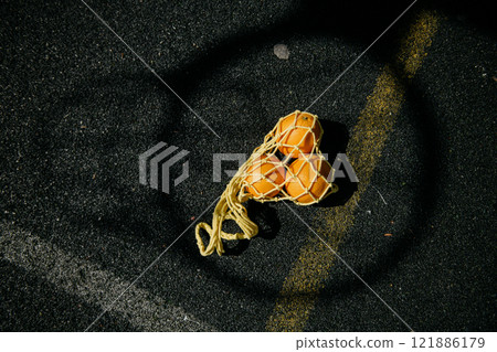 A bag filled with fresh oranges is laying on the ground in a circle A bag filled with fresh oranges is laying on the ground in a circle 121886179