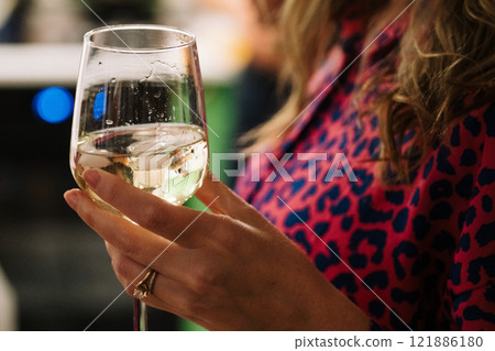 A woman is confidently holding a glass of red wine in her hand A woman is confidently holding a glass of red wine in her hand 121886180