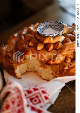 A plate of freshly baked bread accompanied by a bowl of salt placed above it 121886183