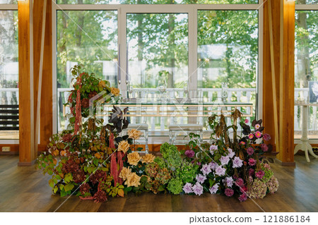 A bunch of flowers sits on the floor in front of a window 121886184