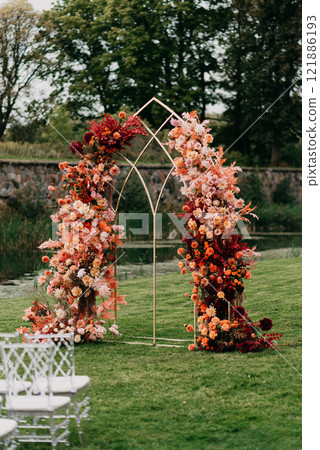 A flowerdecorated wedding arch stands in a lush green field A flowerdecorated wedding arch stands in a lush green field 121886193