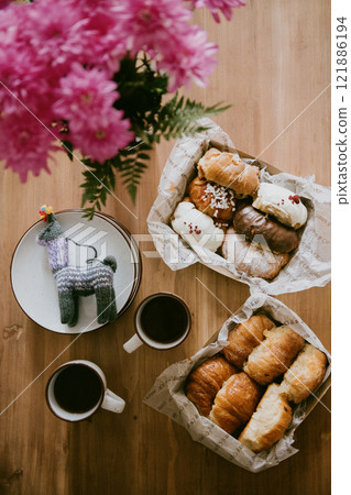 A wooden table with a basket of donuts and two coffee cups 121886194