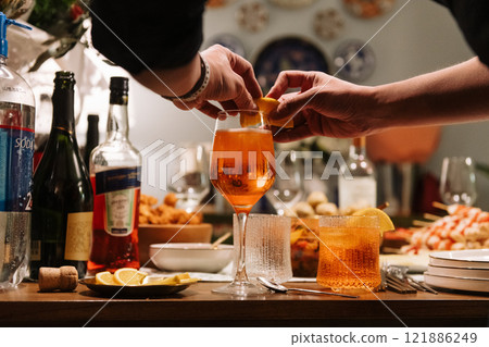 A person is carefully pouring a refreshing drink into a glass on a table 121886249