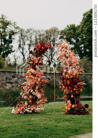 Two beautiful flower arches stand peacefully on a lush green field 121886250