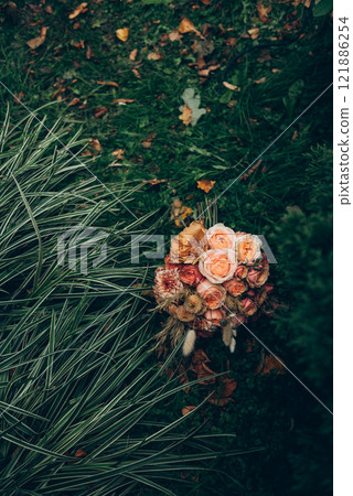 A beautiful bouquet of vibrant flowers is sitting in the lush grass 121886254