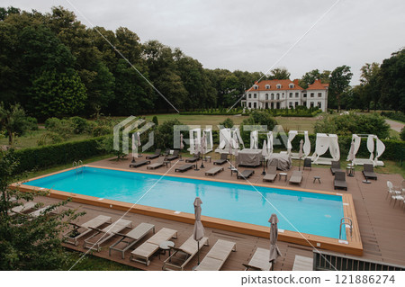 Aerial view of a large swimming pool with chairs and umbrellas 121886274