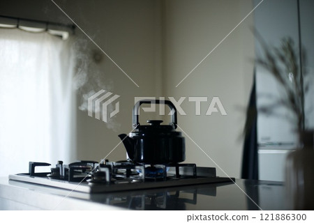 Steam rising from a kettle on the fire 121886300