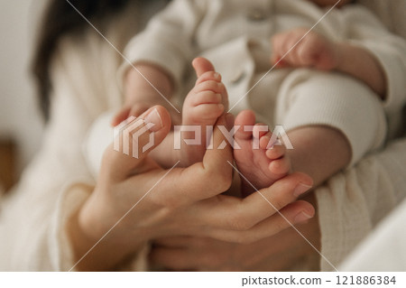 A woman is gently holding a newborn baby securely in her arms A woman is gently holding a newborn baby securely in her arms 121886384