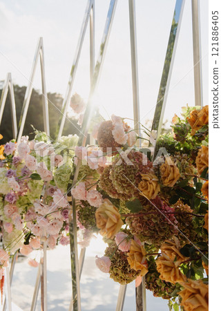 Flowers hanging from a fence with sunlight shining through 121886405