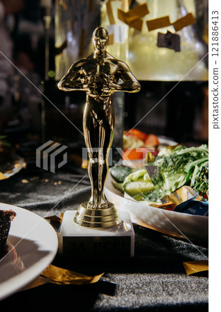 A gold Oscar statue sits on a table beside plates of food A gold Oscar statue sits on a table beside plates of food 121886413