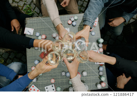 People are sitting around a table toasting with wine glasses People are sitting around a table toasting with wine glasses 121886417