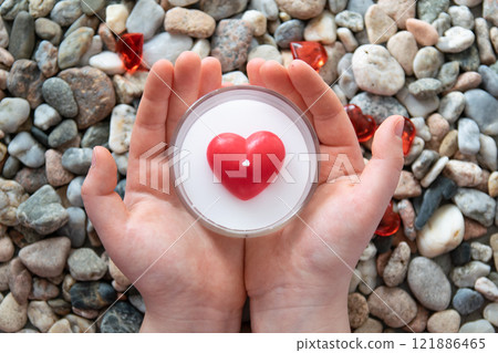 Red bright glasses hearts and candle heart in child hands on the stones background. Concept of Valentine's day and romantic love. Red bright glasses hearts and candle heart in child hands on the stones background. Concept of Valentine's day and romantic love. 121886465