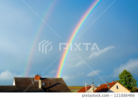 Rainbow over the house after a storm with clouds in the city. Panoramic view of beautiful sunset. Rainbow over the house after a storm with clouds in the city. Panoramic view of beautiful sunset. 121886466
