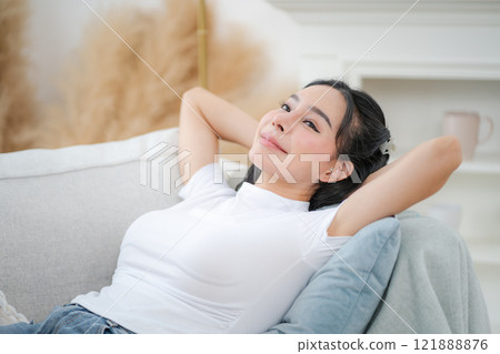 Copy space shot of young woman reclining on sofa with hands behind head and relaxing happily Copy space shot of young woman reclining on sofa with hands behind head and relaxing happily 121888876