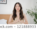Asian woman doing a yoga pose with hands clasped on the bed 121888933