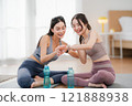 Two Asian women looking at smartwatches to measure their physical fitness during a break from exercise, health and wellness concept, exercise 121888938