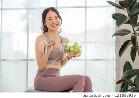 Fitness loving young asian woman sitting eating salad, health concept, exercise, healthy eating 121888939