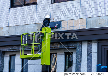一名工人在高空作業車上修理牆壁 一名工人在高空作業車上修理牆壁 121890290