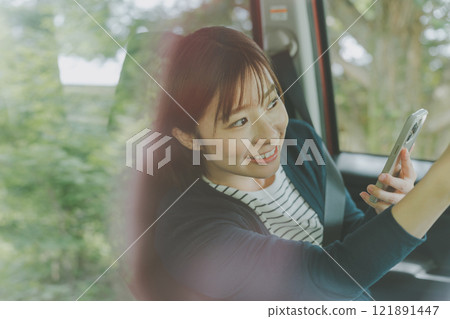 乘客座位上的一位女士使用智慧型手機地圖應用程式搜尋路線 121891447