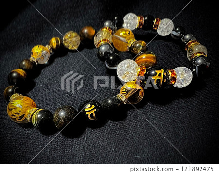 A black and gold stone bracelet on a black background 121892475