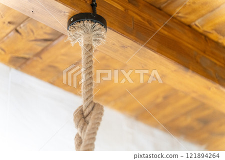 Rustic Rope Hanging from Wooden Ceiling Beam Rustic Rope Hanging from Wooden Ceiling Beam 121894264