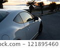 A white sports car parked by the sea at sunset 121895460