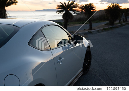 日落時海邊停著一輛白色跑車 日落時海邊停著一輛白色跑車 121895460
