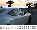 A white sports car parked by the sea at sunset 121895463