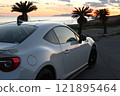 A white sports car parked by the sea at sunset 121895464