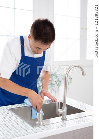 Senior male housekeeper cleaning the kitchen 121895821
