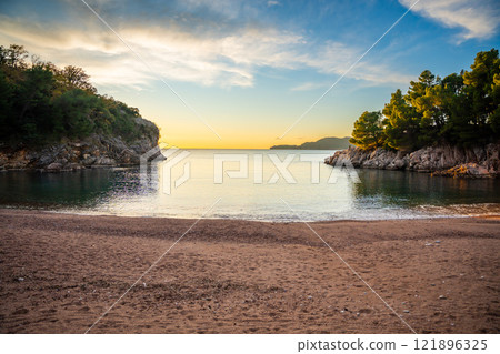 Wild beach near Sveti Stefan at sunset, near Budva, Montenegro. Waves and rocks at sunset lights 121896325