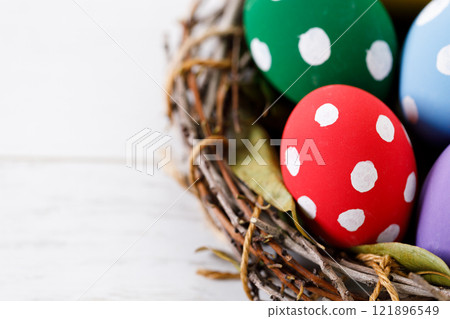 Colorful Easter eggs in a basket on white wooden table. Colorful Easter eggs in a basket on white wooden table. 121896549