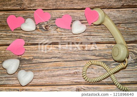 old cable headset with a pile of pink and white hearts on a wooden table 121896640