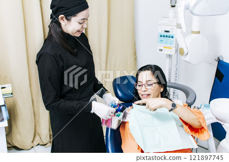 Patient with dentist choosing dental braces, Dentist with patient choosing metal braces, Patient with dentist choosing rubber band 121897745