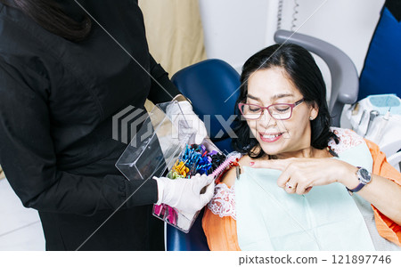 Patient with dentist choosing dental braces, Dentist with patient choosing metal braces, Patient with dentist choosing rubber band Patient with dentist choosing dental braces, Dentist with patient choosing metal braces, Patient with dentist choosing rubber band 121897746