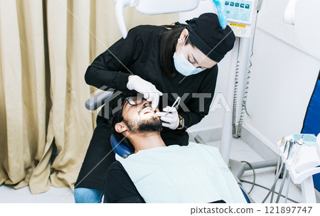 Dentist performing dental checkup, dentist checking braces to patient, patient checked by dentist Dentist performing dental checkup, dentist checking braces to patient, patient checked by dentist 121897747